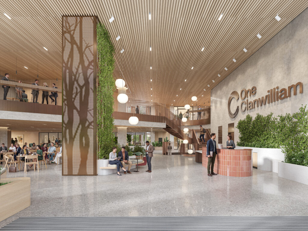 Modern office lobby with greenery, people sitting and talking, reception desk, and a staircase to the upper floor.